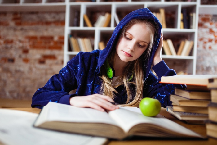 Teenage girl reading a book in library